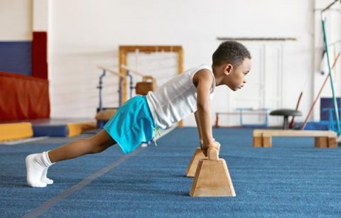 sideways shot concentrated serious afro american kid sports clothes keeping feet floor