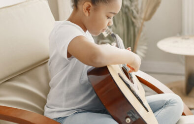 little-girl-with-curly-hair-learning-play-guitar-little-girl-chair
